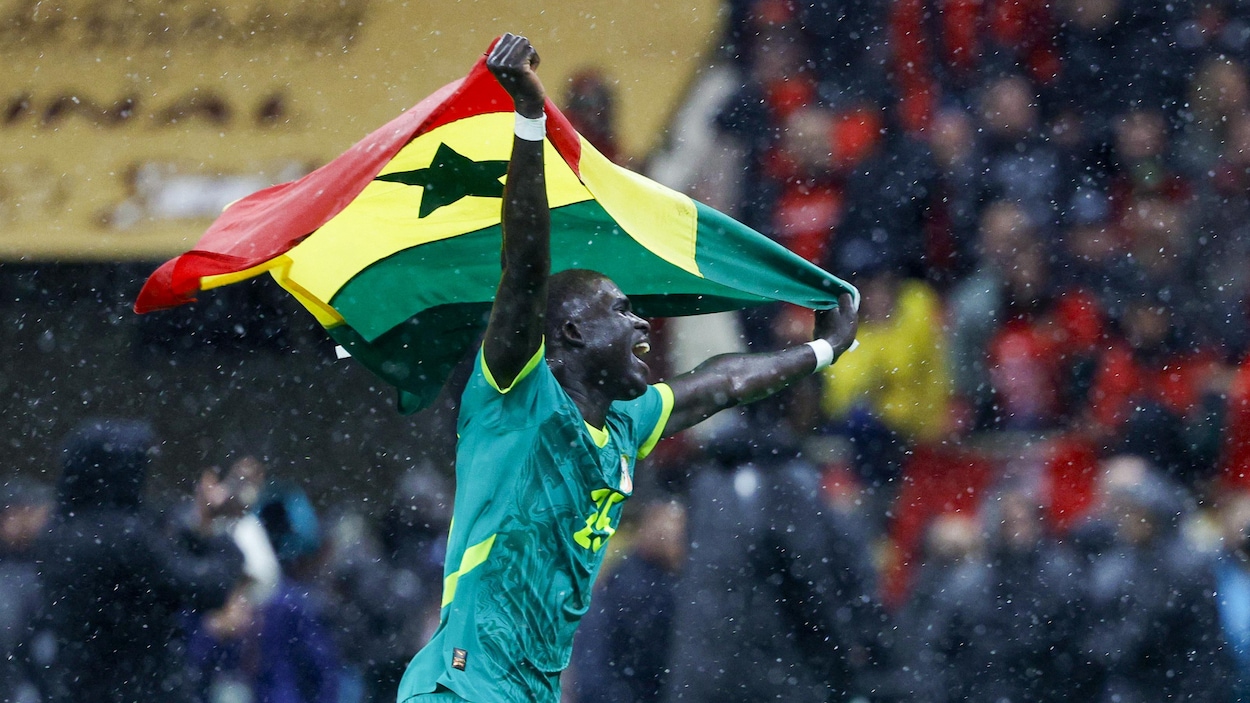 El Hadji Malick Diouf célèbre avec le drapeau du Sénégal sous la pluie